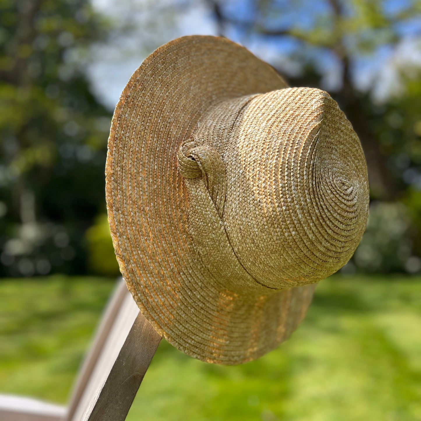Worn straw hat on a chair with a blurred green outdoor background
