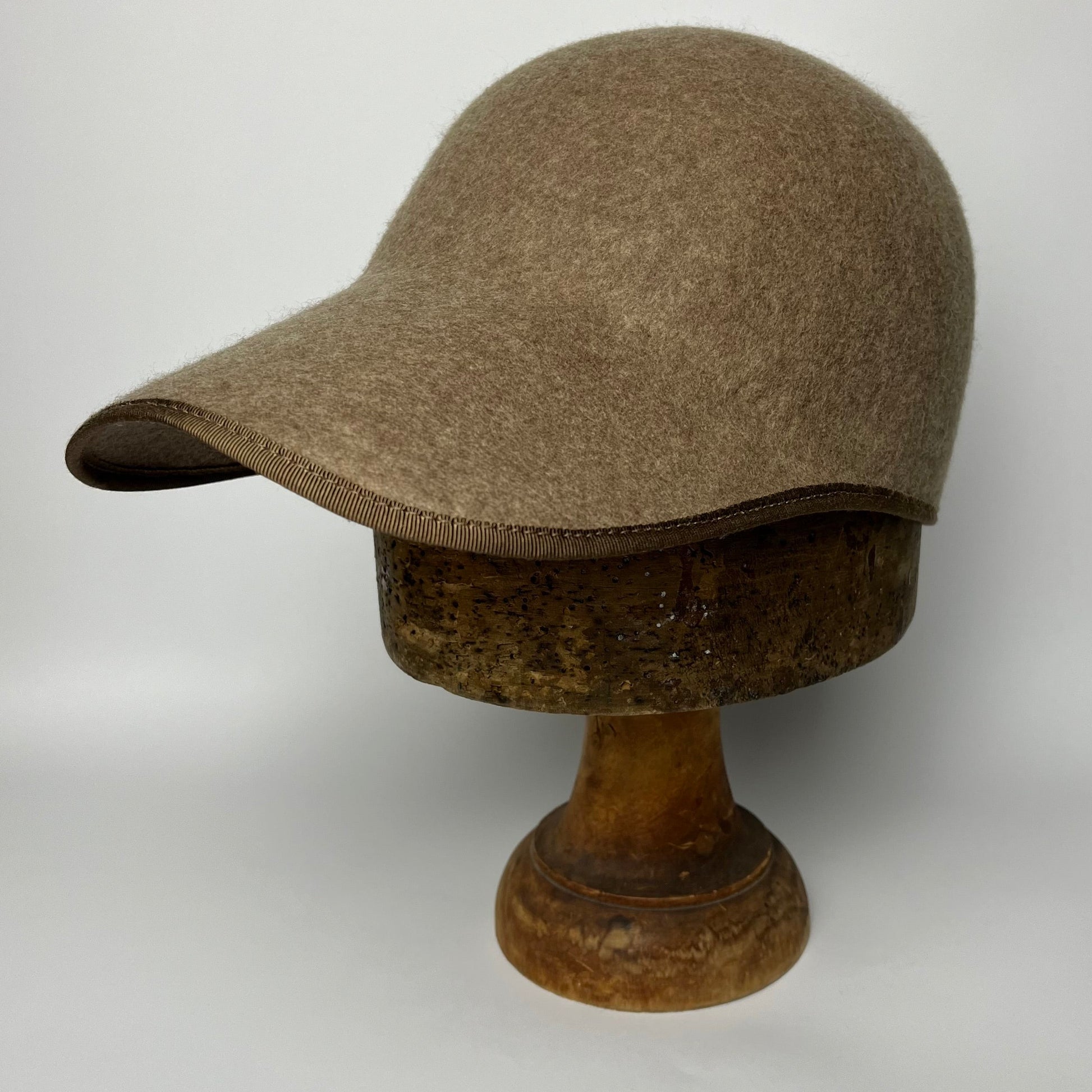 Brown cap on a wooden mannequin head against a white background
