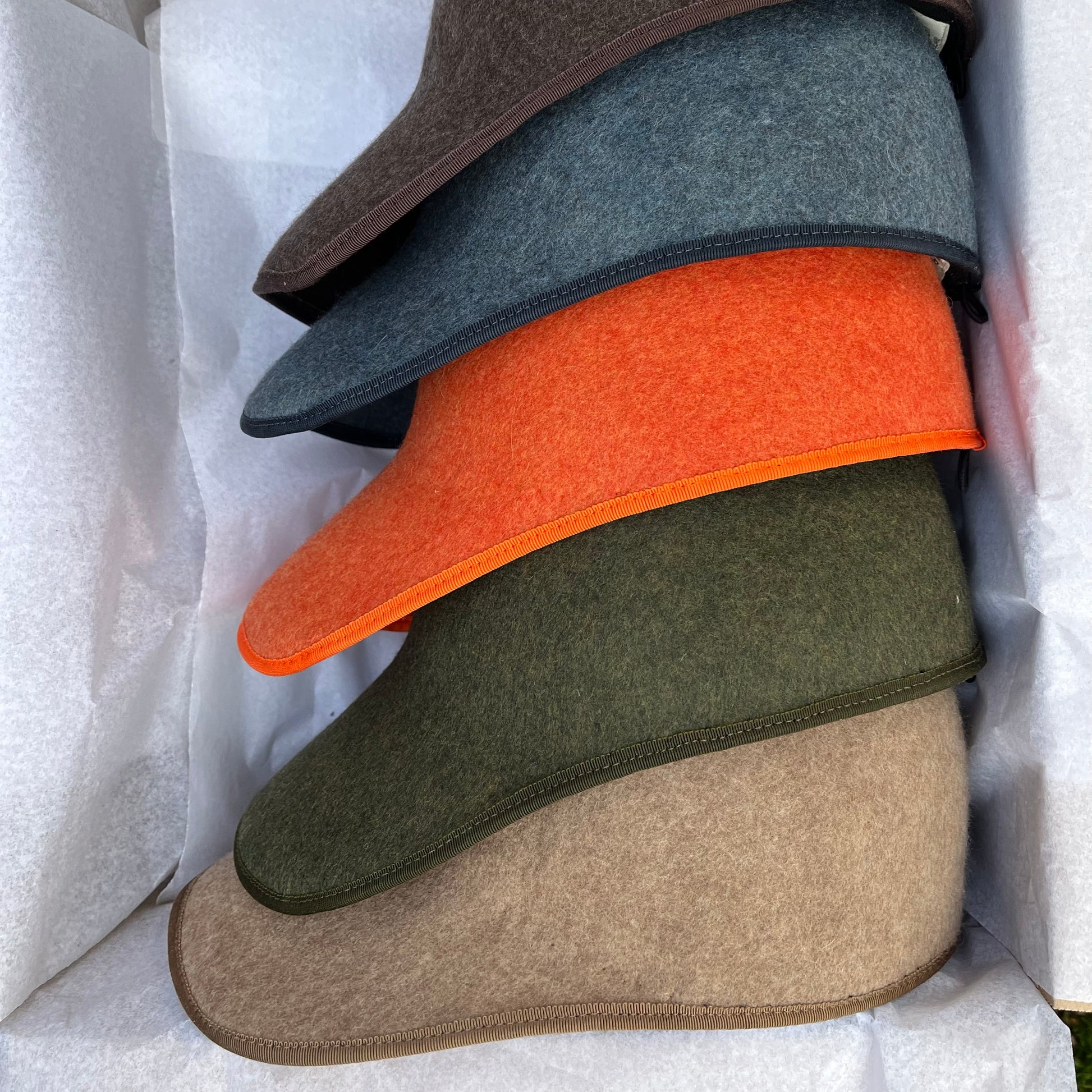 Stack of felted hats in various colors on a white background