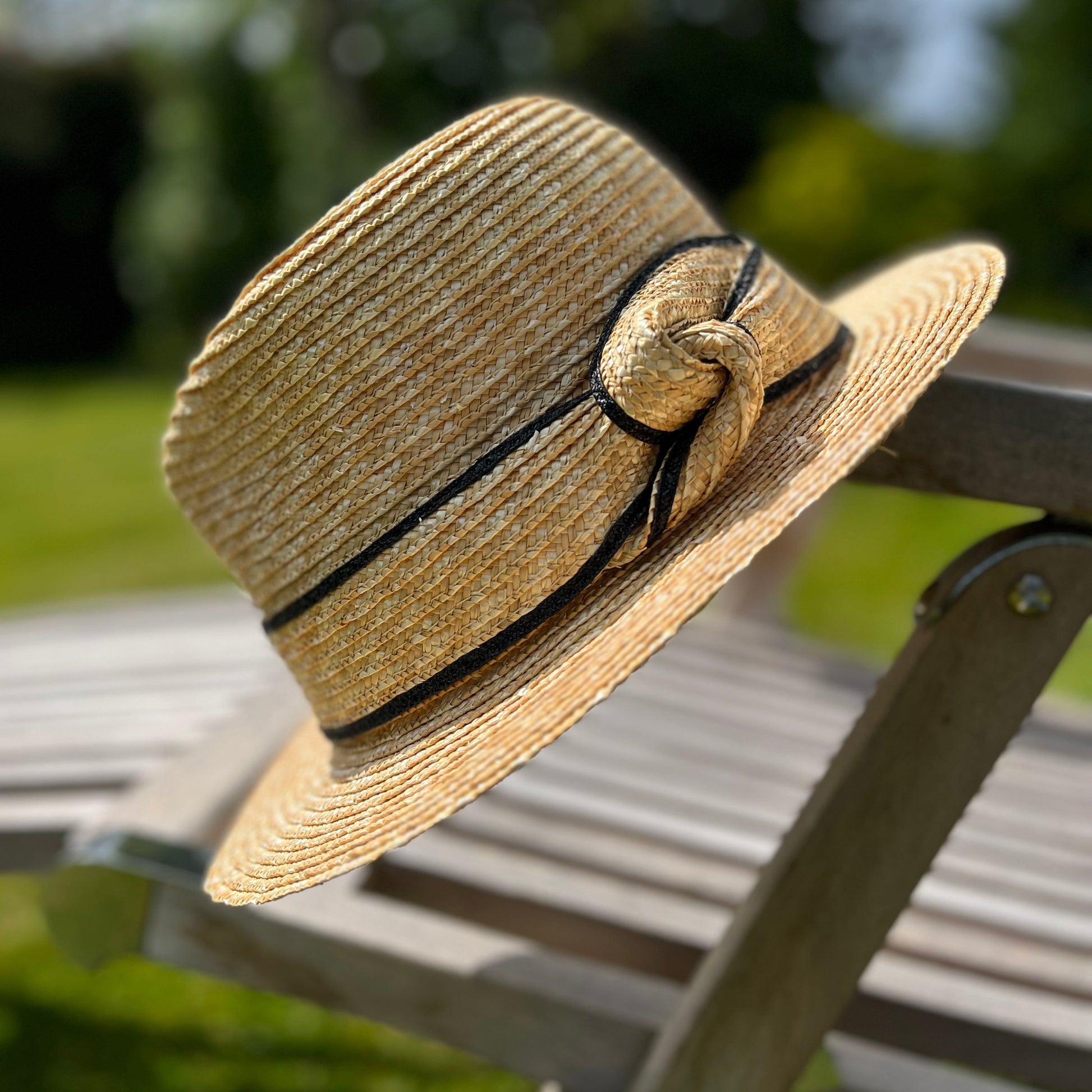 Straw hat with a straw ribbon on a chair outdoors
